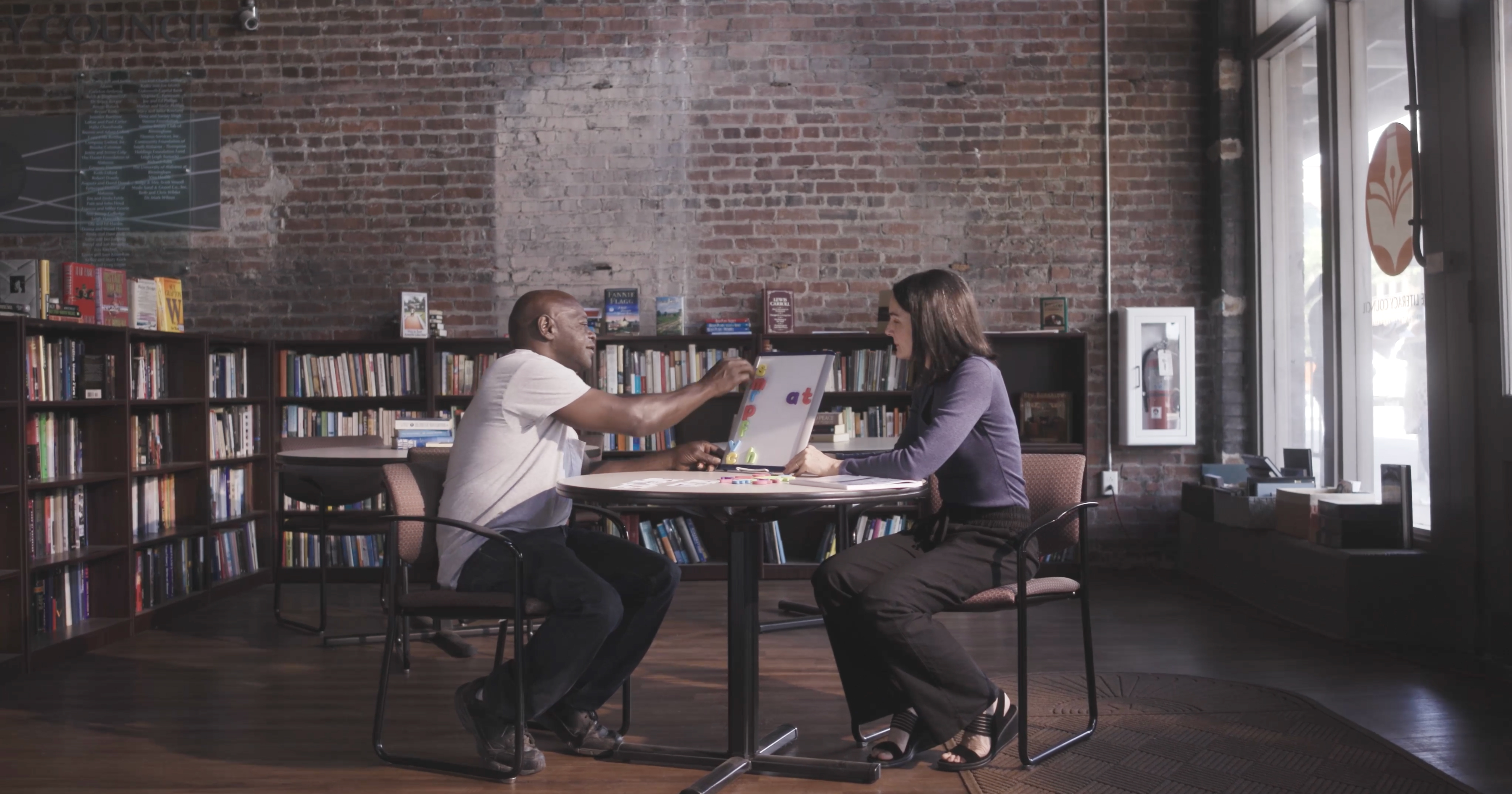 Image of Literacy Council volunteer helping a client improve his reading skills using a whiteboard and magnets