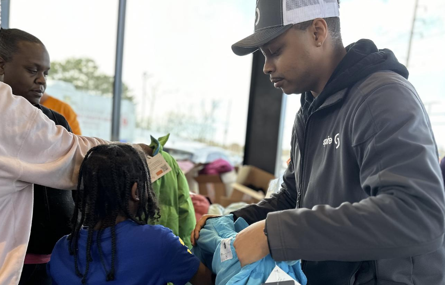 Image of Spire supervisor putting a coat on a child to try on