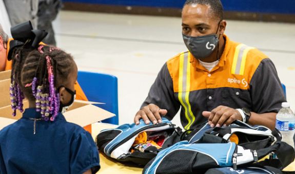 Spire employee gifting backpacks at school