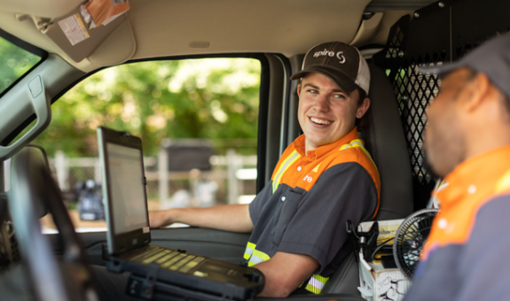 Happy Spire employee in work truck with co-worker