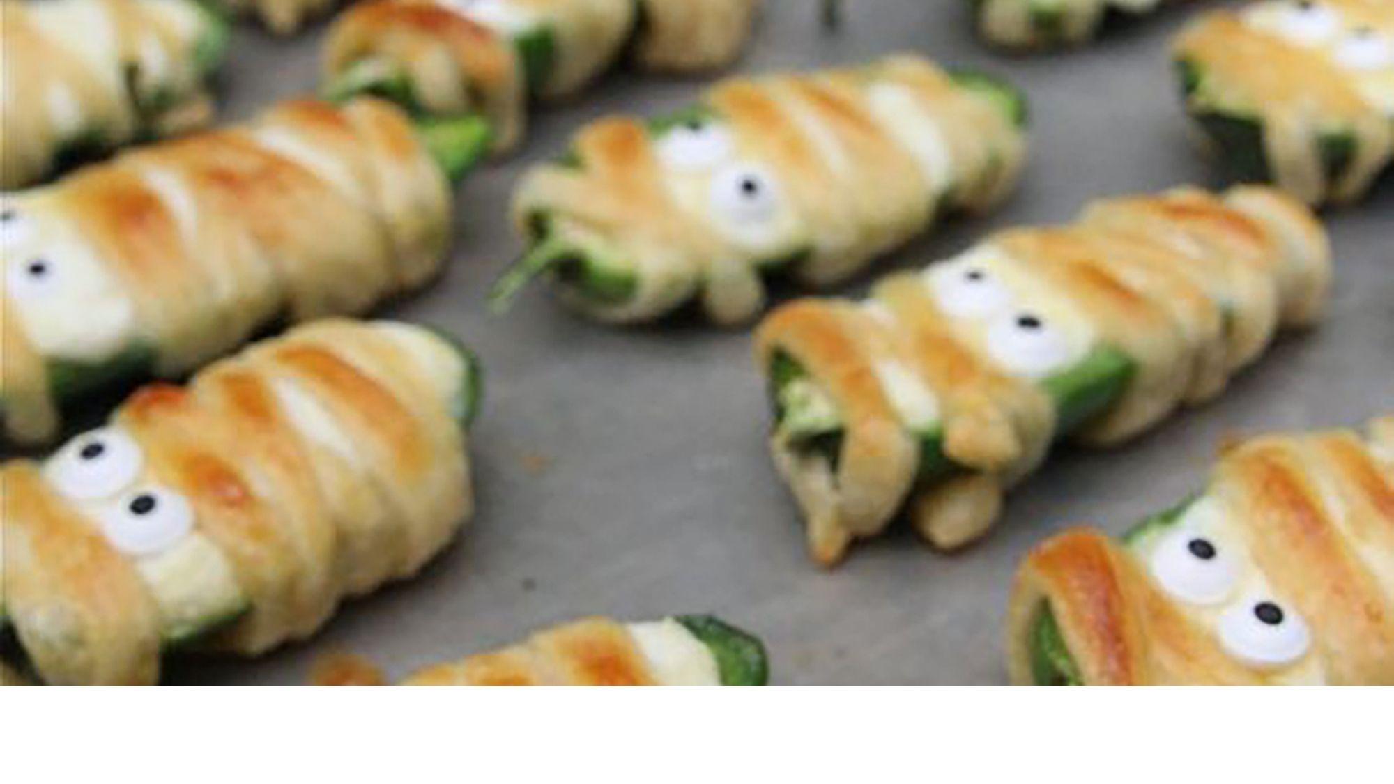 Jalapeno poppers on a baking sheet decorated as mummies