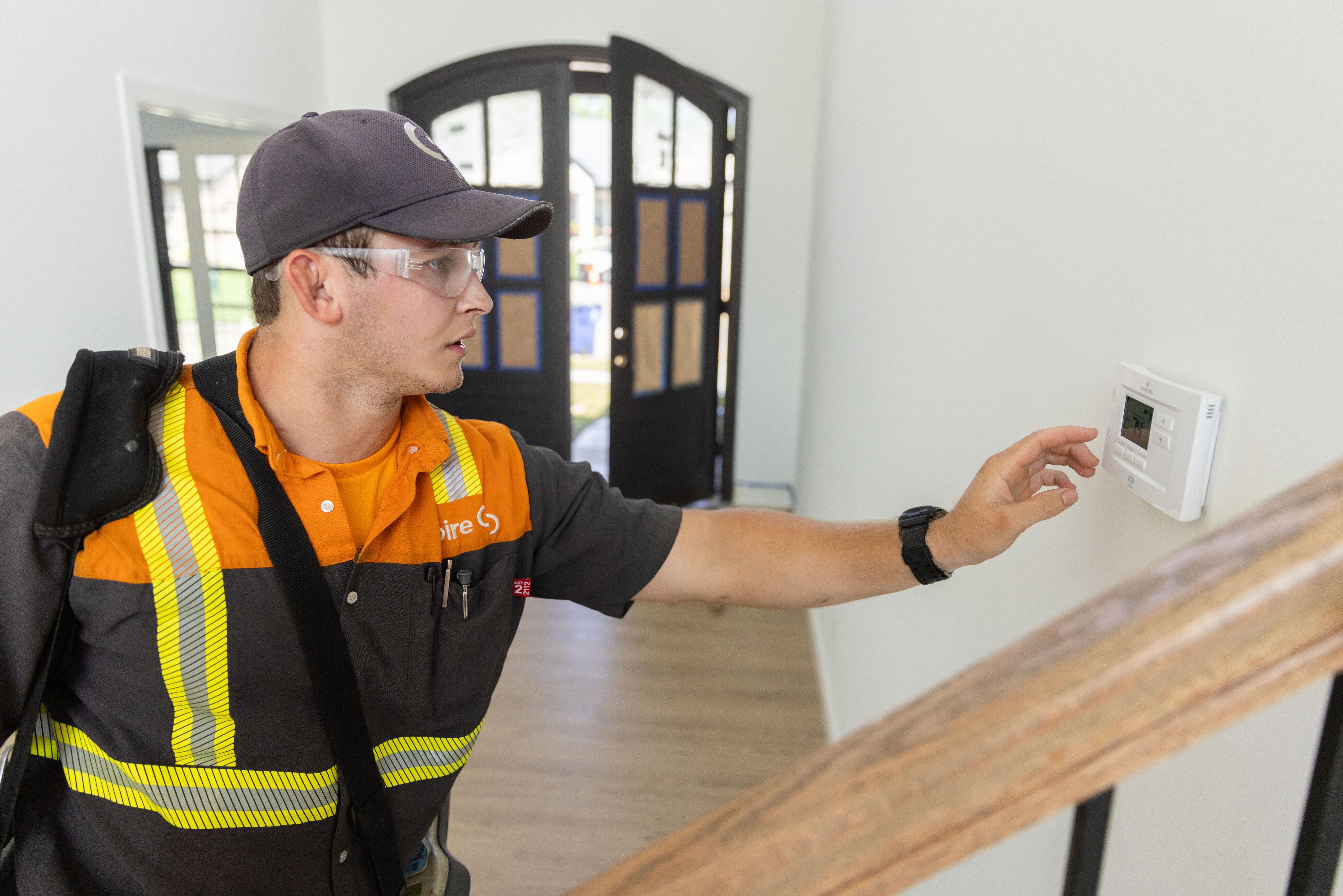 Image of service technician adjusting a thermostat inside a home