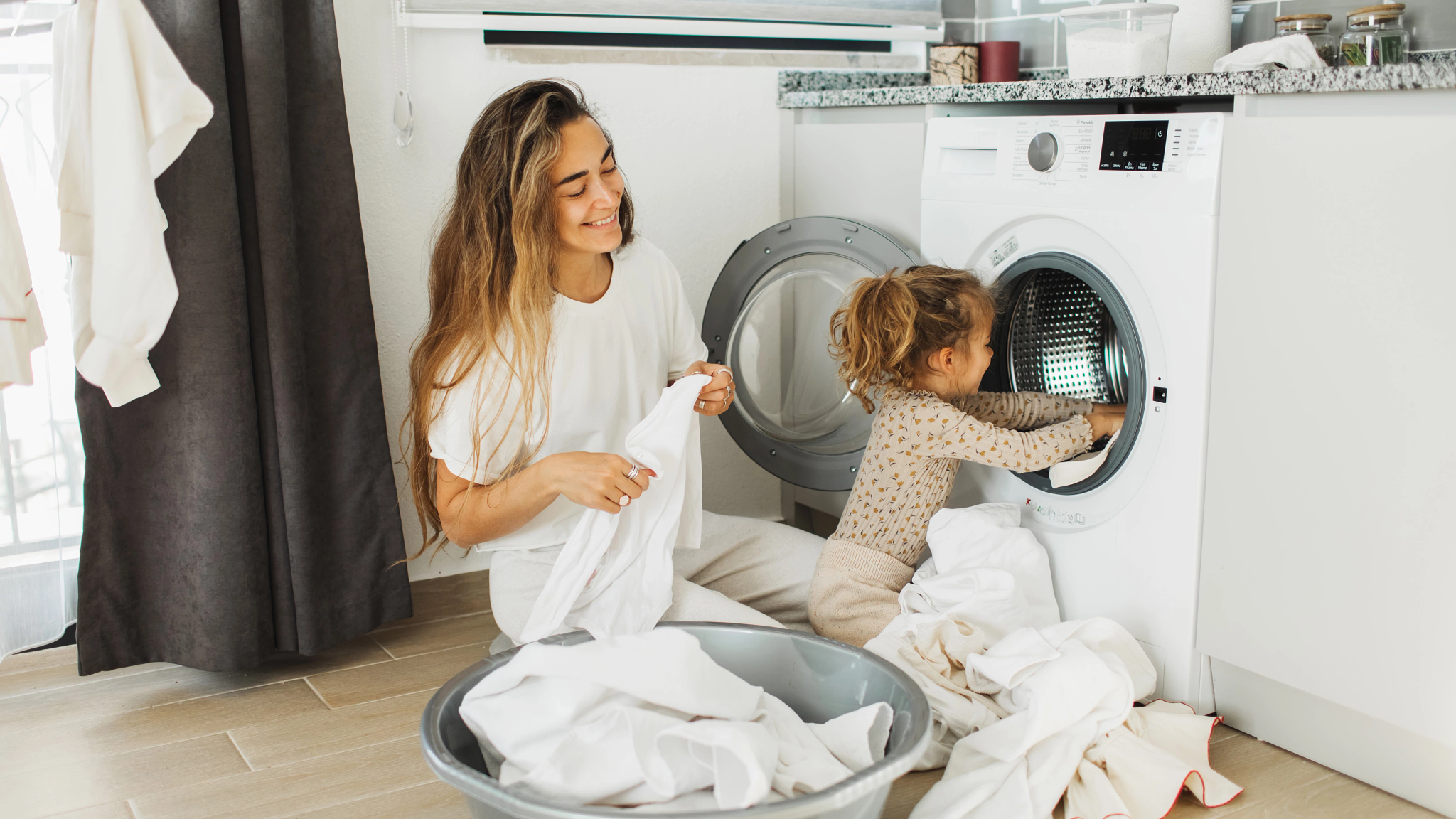 Image of mother and daughter folding clothes out of the dryer